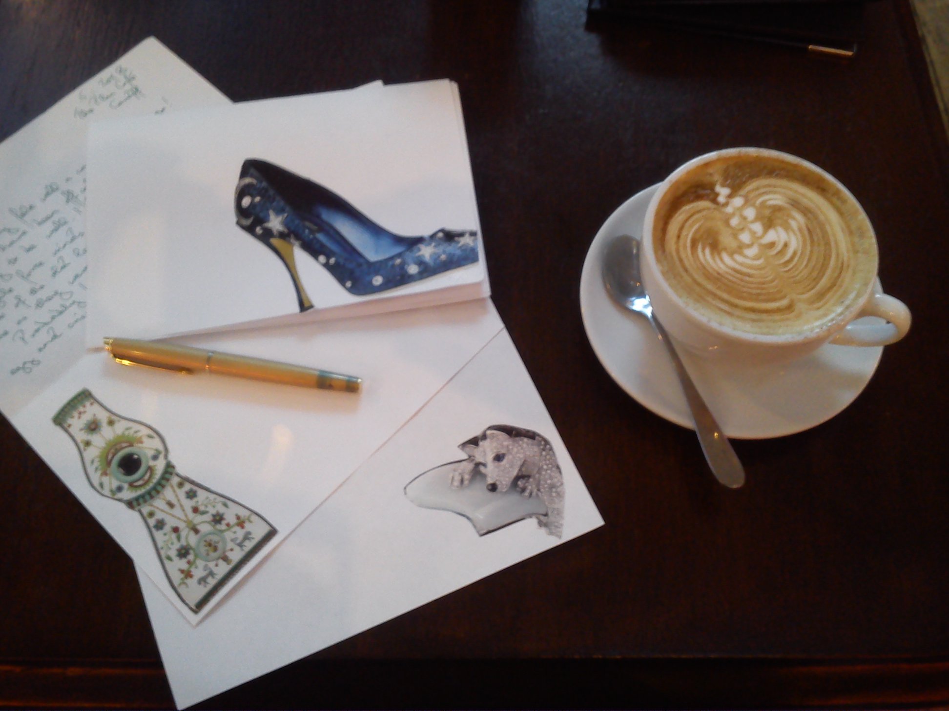 Half-written letter decorated with decoupage pictures, a fountain pen and a cup of coffee.