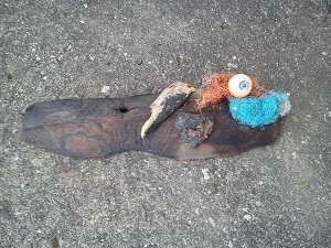 Driftwood, scrunched up orange and blue plastic fishing line and a blue and orange plastic eyeball
