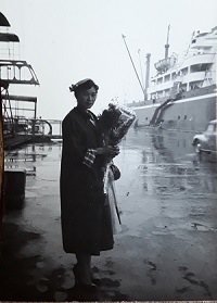 Japanese lady in elegant western dress holding bouquet of flowers and waiting to board a ship