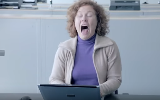A woman sneezing in front of a laptop