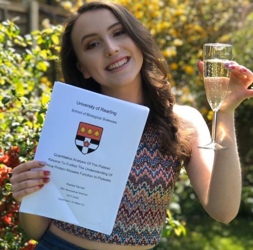 Young woman with a degree dissertation and a glass of champagne