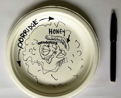 A paper plate on which a black pen drawing of a bowl of porridge has been attempted