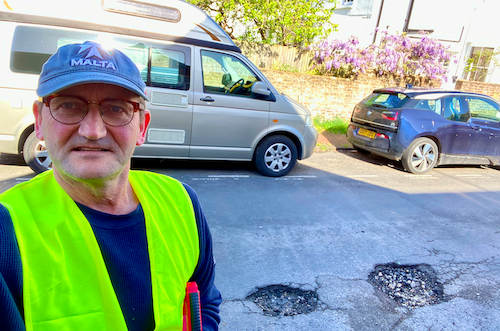 Jonathan Vernon in a high-vis jacket surveying potholes on Talbot Terrace