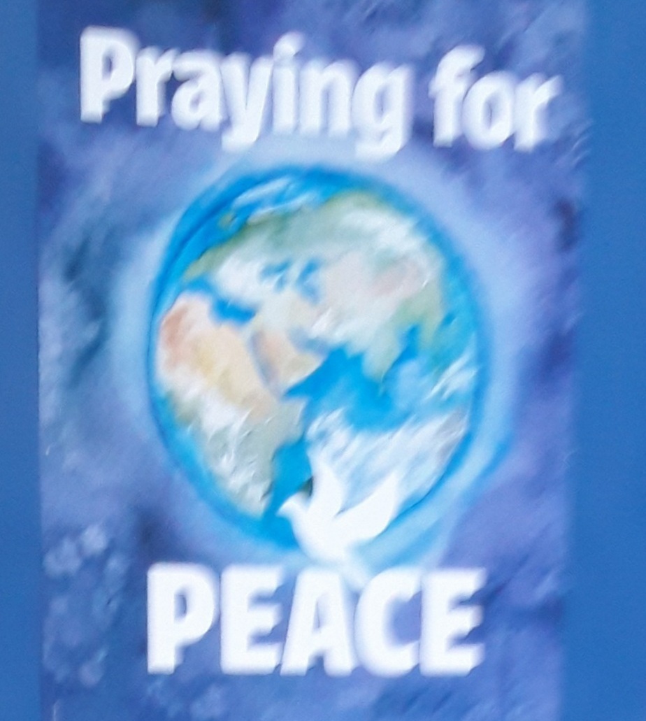 A poster showing the earth in space with the words " Praying for Peace" on it.