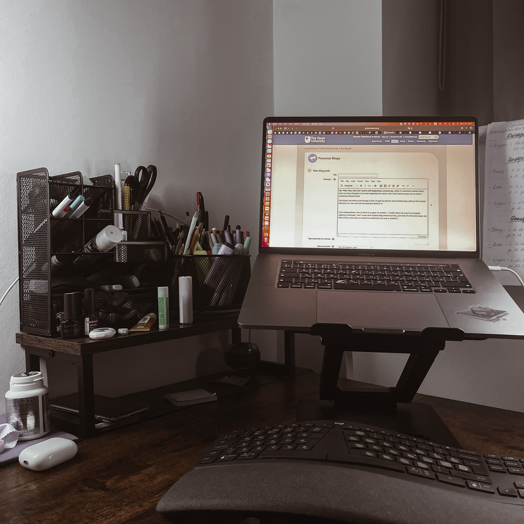 my working desk by the high window at a very early morning, so still dark outside. It has my laptop on a stand and keyboard under it as well as stationary organiser on the side full of pens, pencils and other stuff used in office.